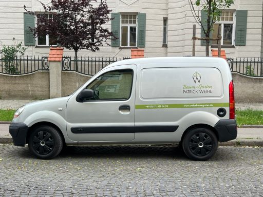 Ein silberner Lieferwagen mit grüner Aufschrift steht an der Straßenseite.